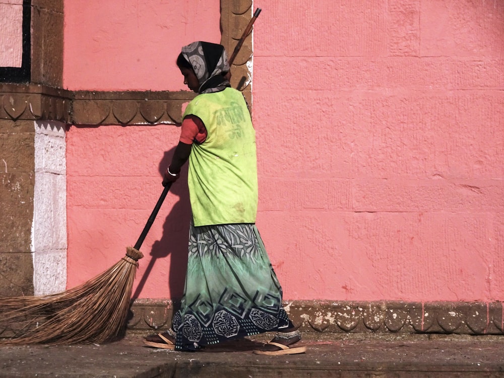 woman in green and black dress holding broom