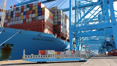 A large container ship docked at Toronto port, loaded with construction equipment ready for export.