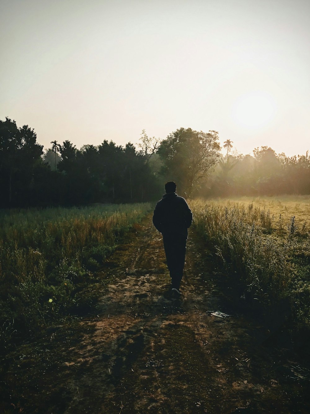 man in black jacket standing on brown dirt road during daytime