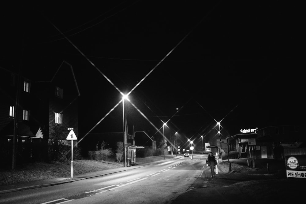 grayscale photo of man walking on sidewalk