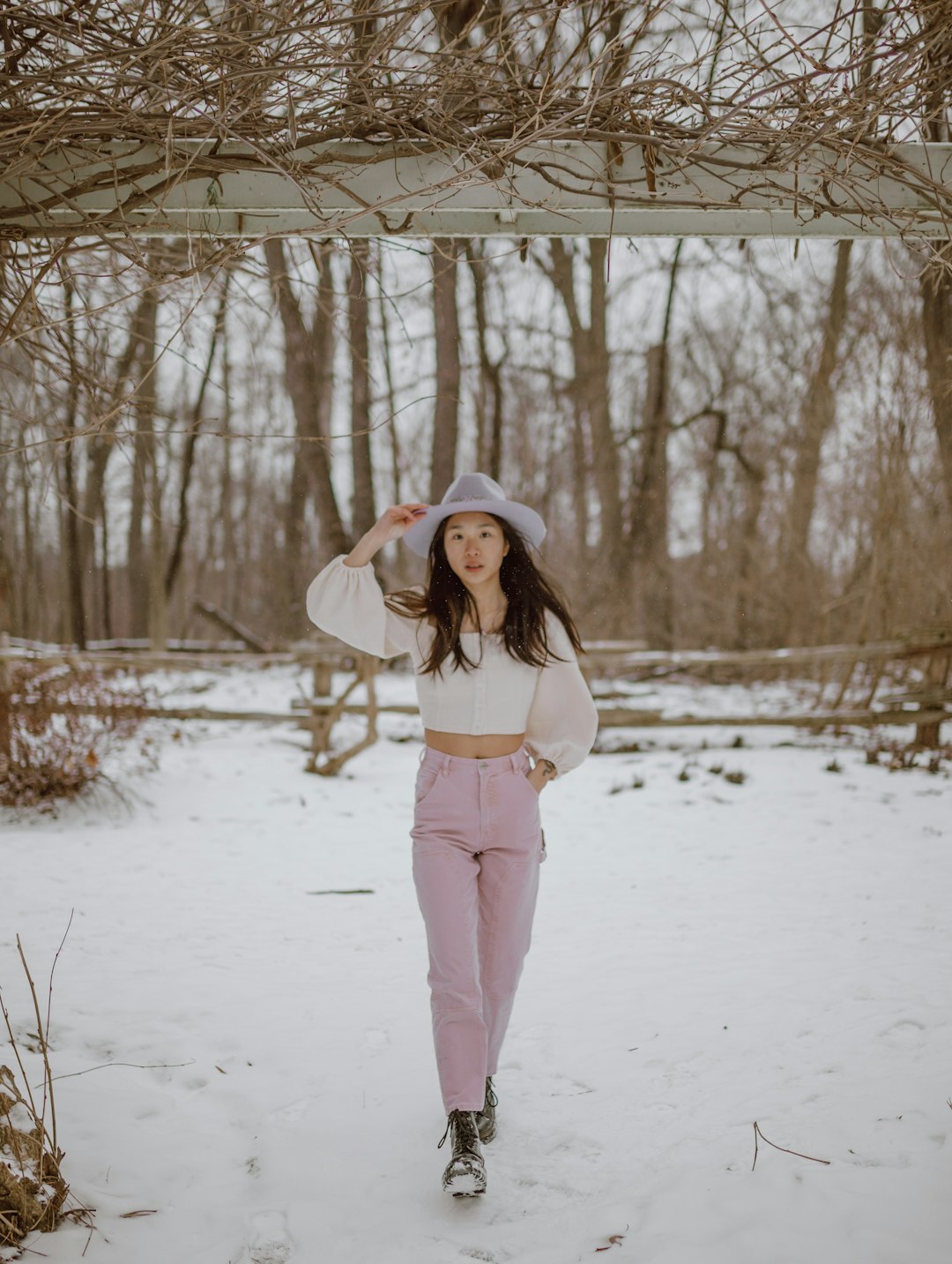 woman in white long sleeve shirt and pink pants standing on snow covered ground during daytime