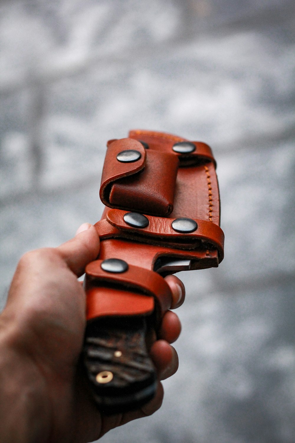 person holding brown leather case