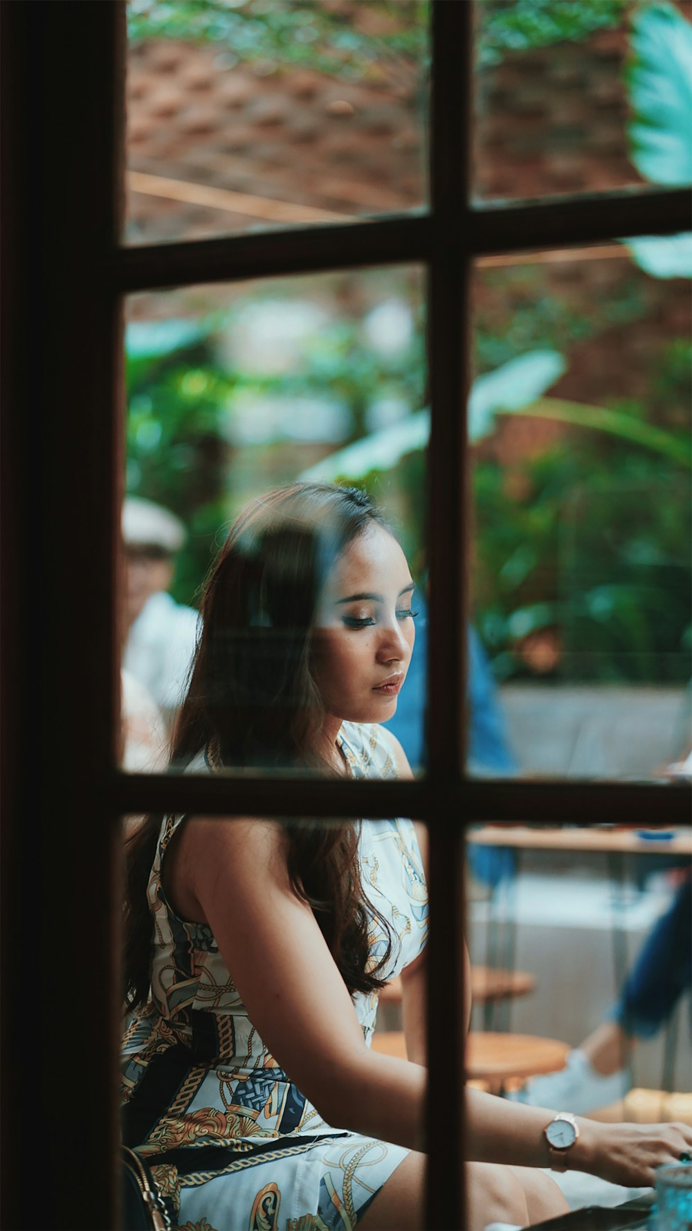 woman in white tank top looking at the window