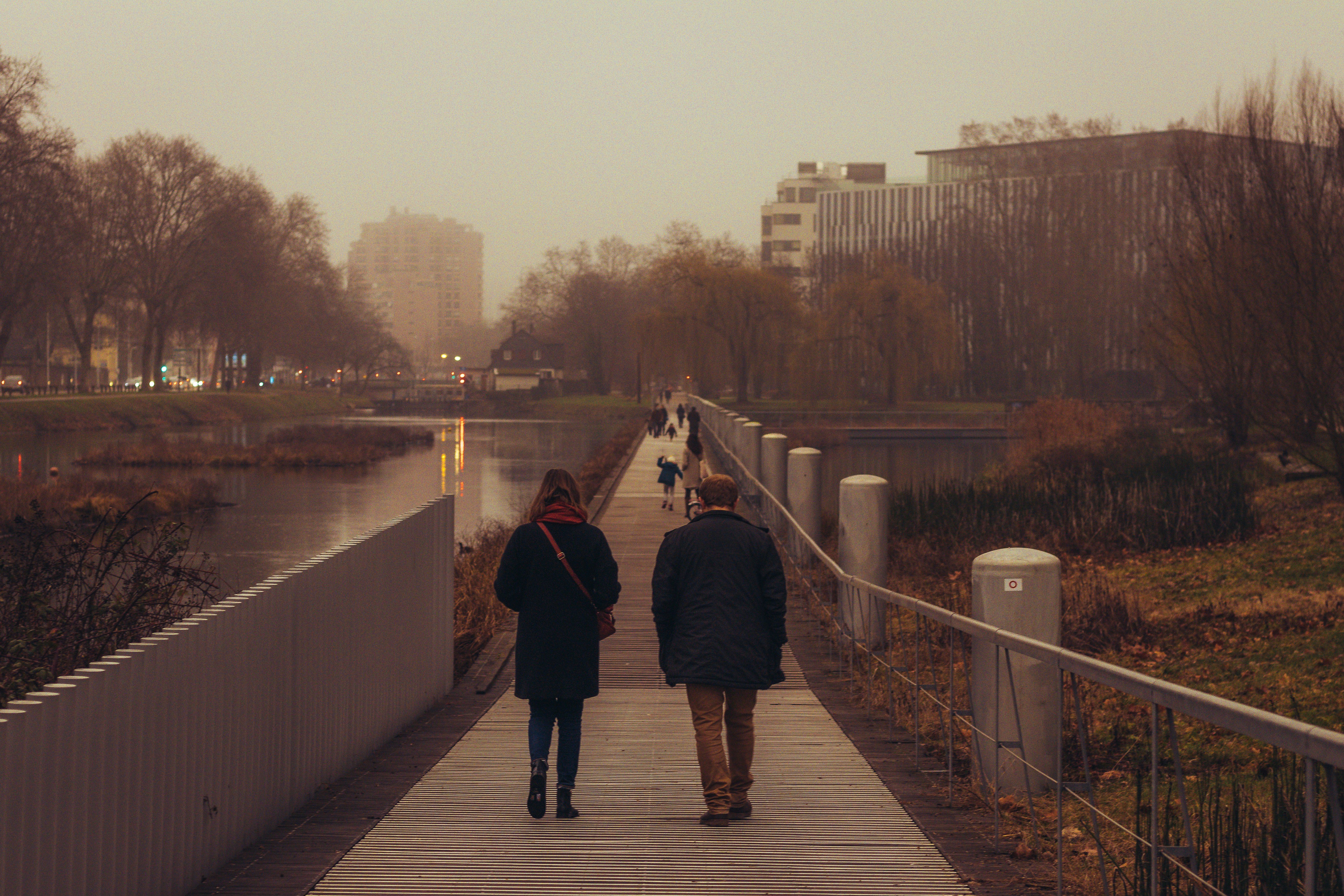 man in black jacket and black pants walking on bridge during daytime