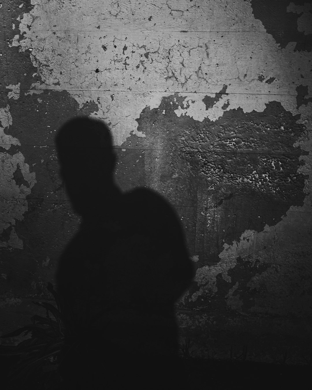 silhouette of man standing in front of brick wall