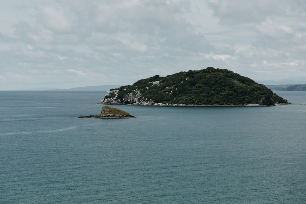 green island on blue sea under white clouds during daytime