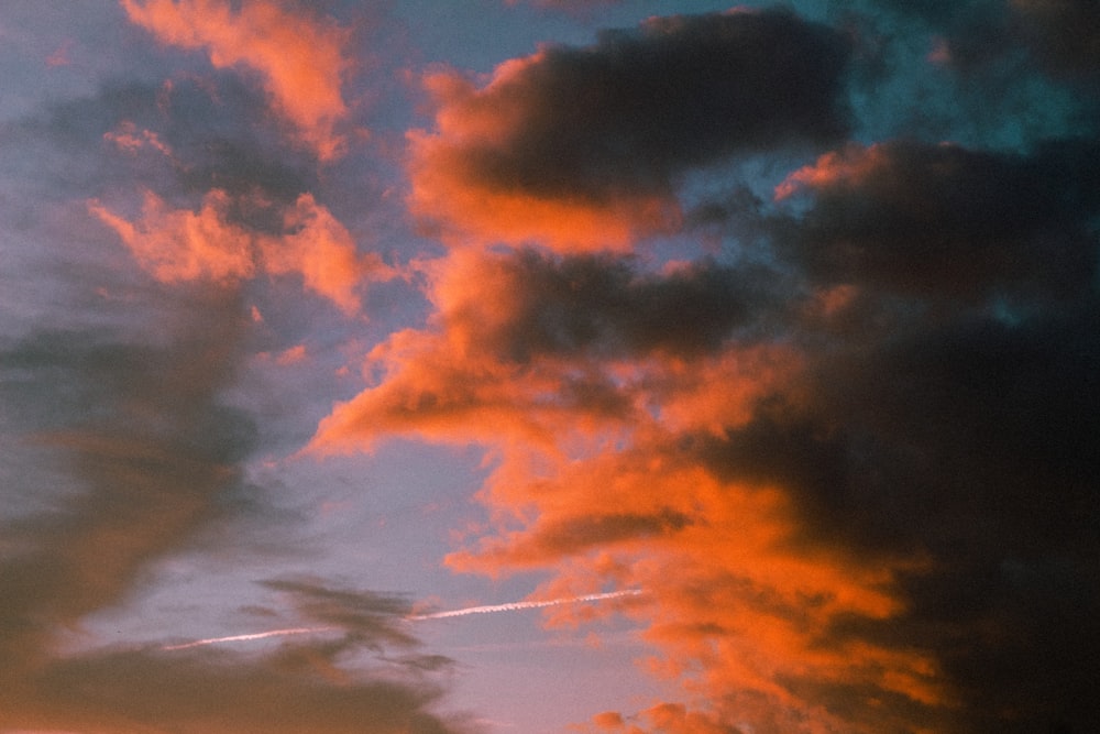 a plane flying through a cloudy sky at sunset