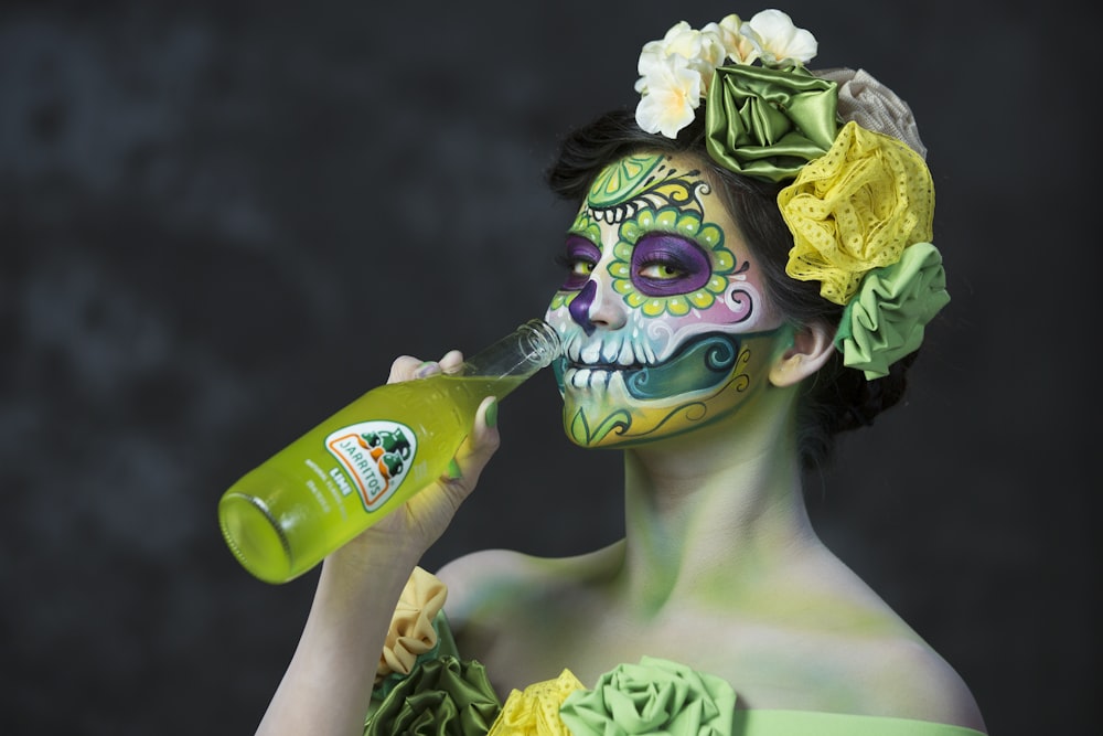 woman in yellow floral headdress holding green bottle