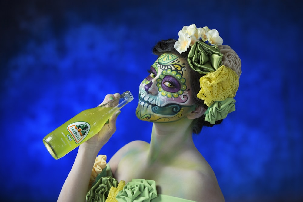 woman in green and purple floral headdress holding bottle