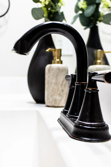 Close-up of a sleek black and orange tap installed on a modern white basin.