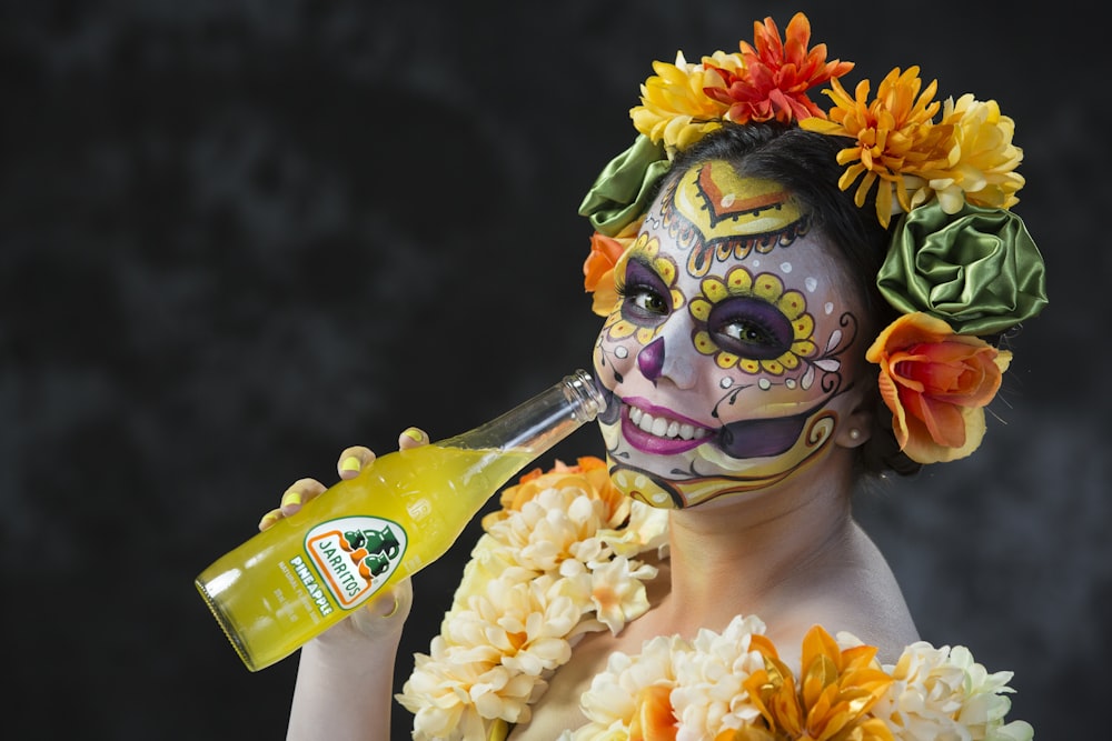 person in yellow green and red floral headdress holding yellow and white plastic bottle
