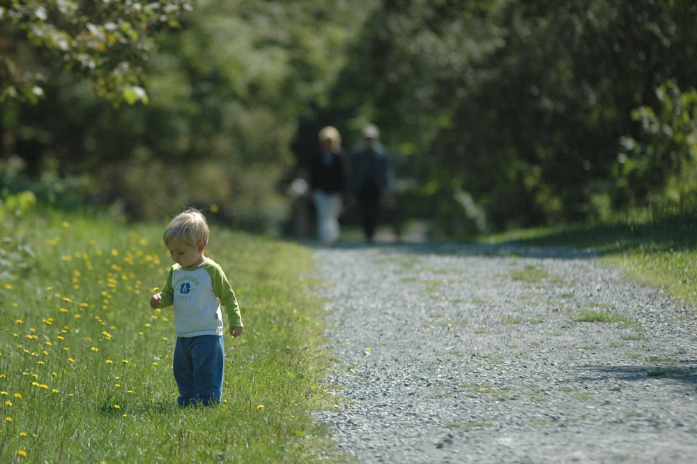 boy in yellow t-shirt and blue denim jeans standing on green grass field during daytime