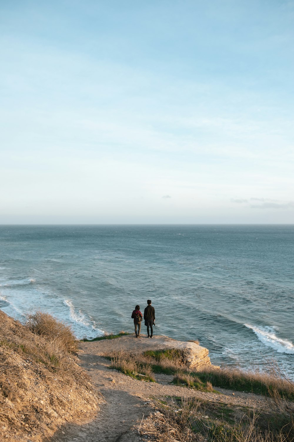 person standing on cliff near body of water during daytime