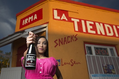 woman in pink long sleeve shirt holding black bottle
