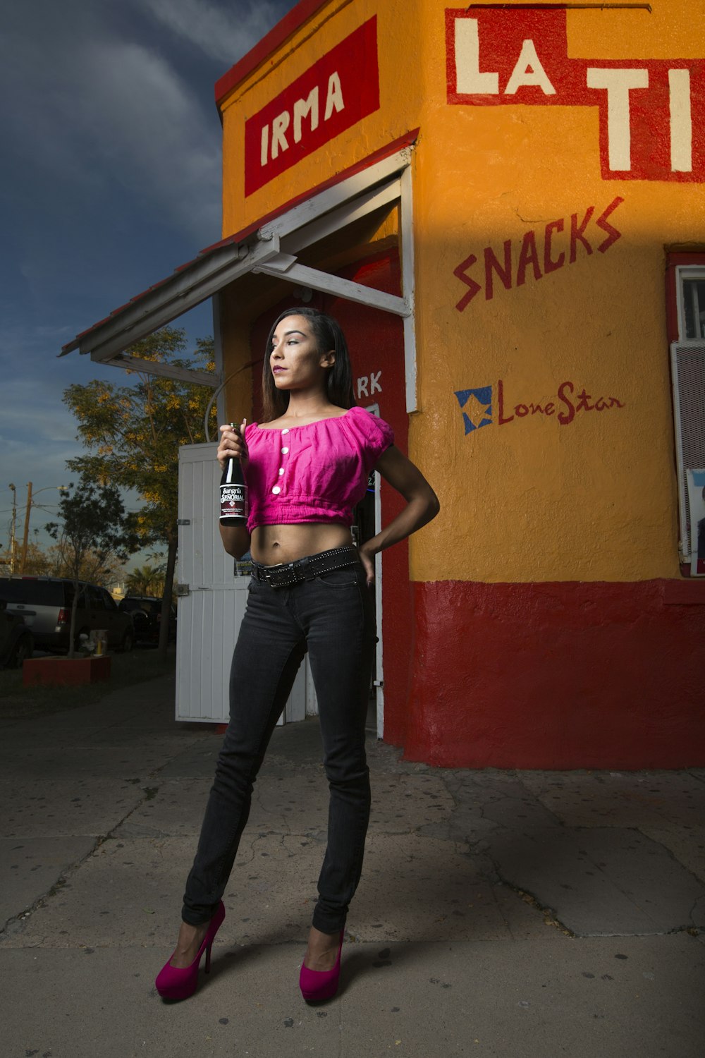 woman in pink shirt and blue denim jeans standing beside red and yellow painted wall