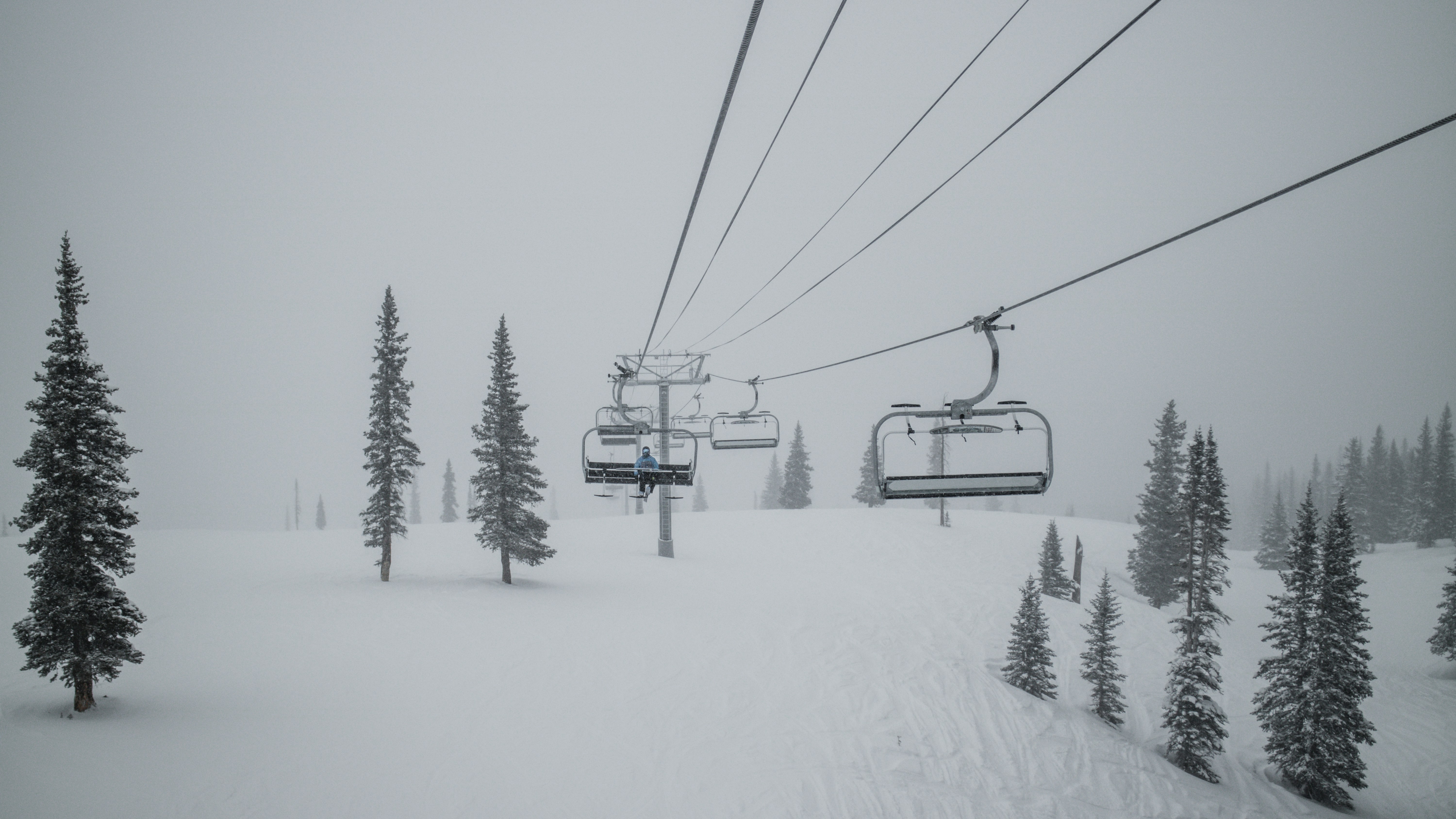 black cable car over snow covered ground, Man on chairlift in snowstorm 1