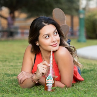 woman in red tank top holding red plastic bottle