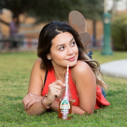 woman in red tank top holding red plastic bottle