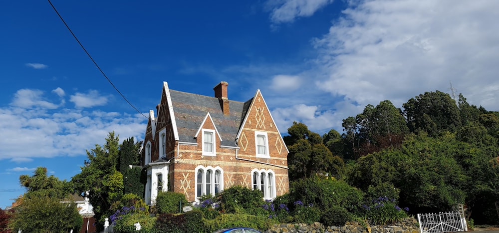 Casa de hormigón marrón y blanco rodeada de árboles verdes bajo el cielo azul durante el día