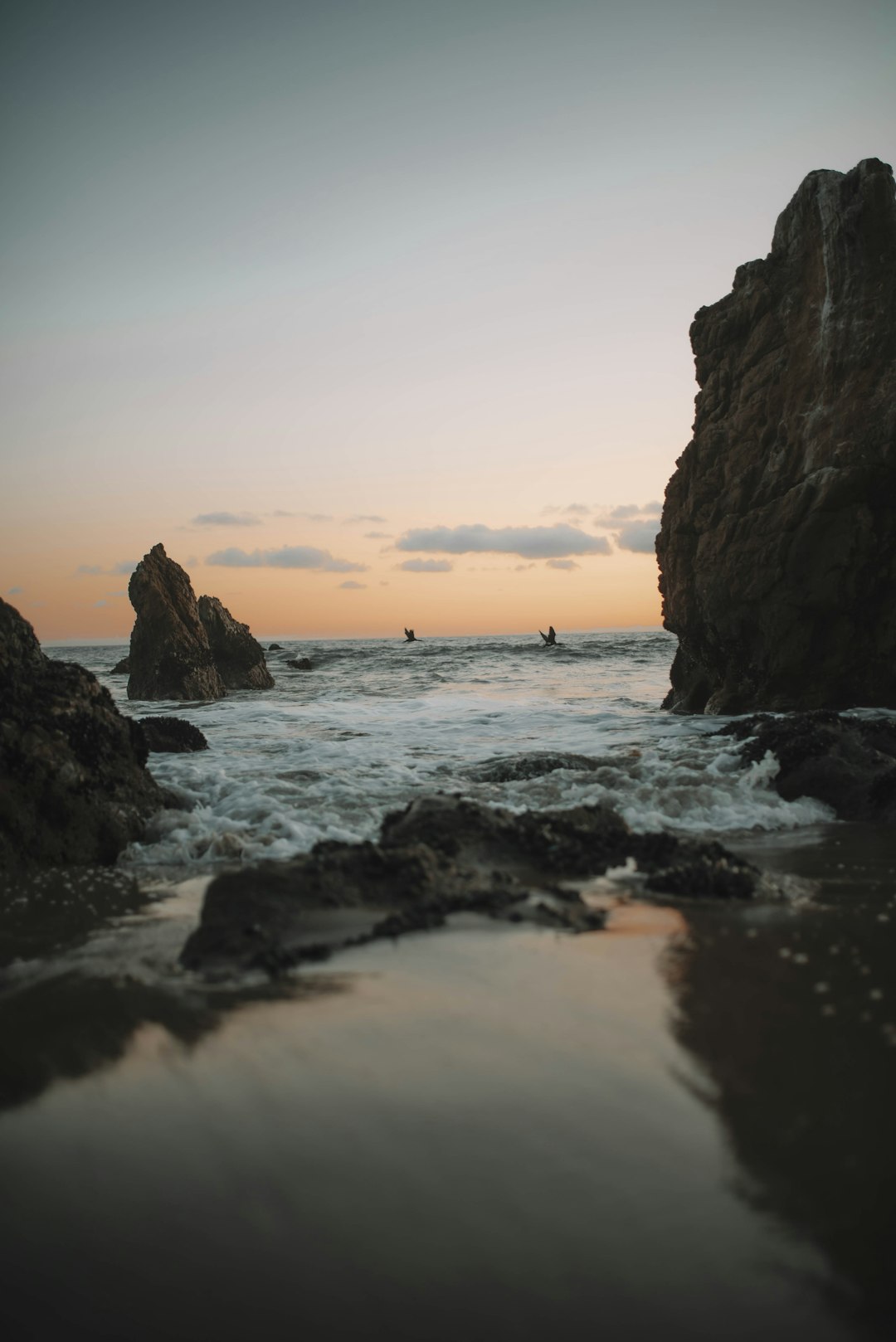 brown rock formation on sea during sunset