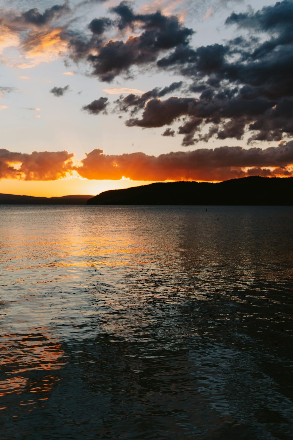 body of water under cloudy sky during sunset