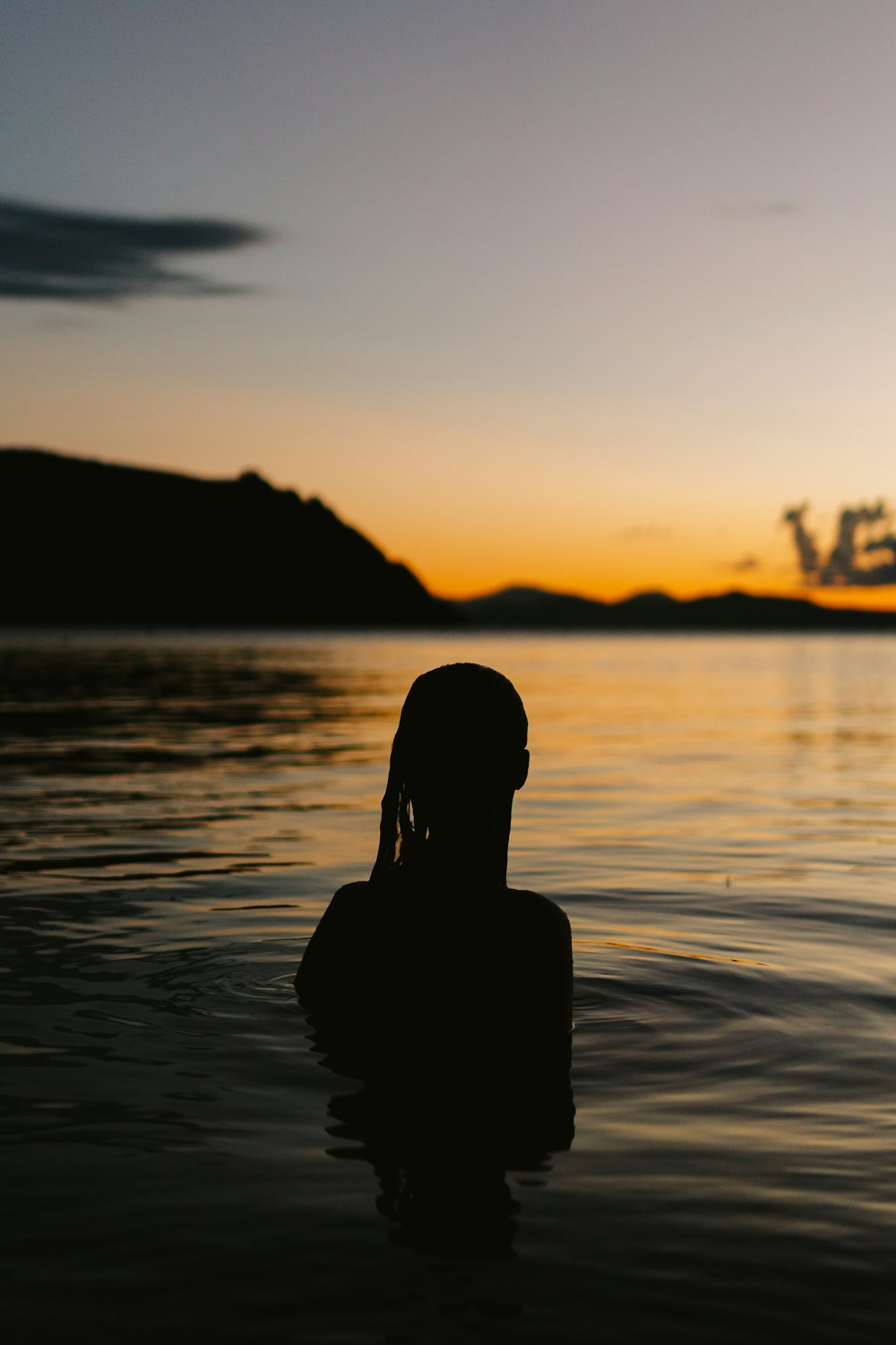 silhouette of woman on water during sunset