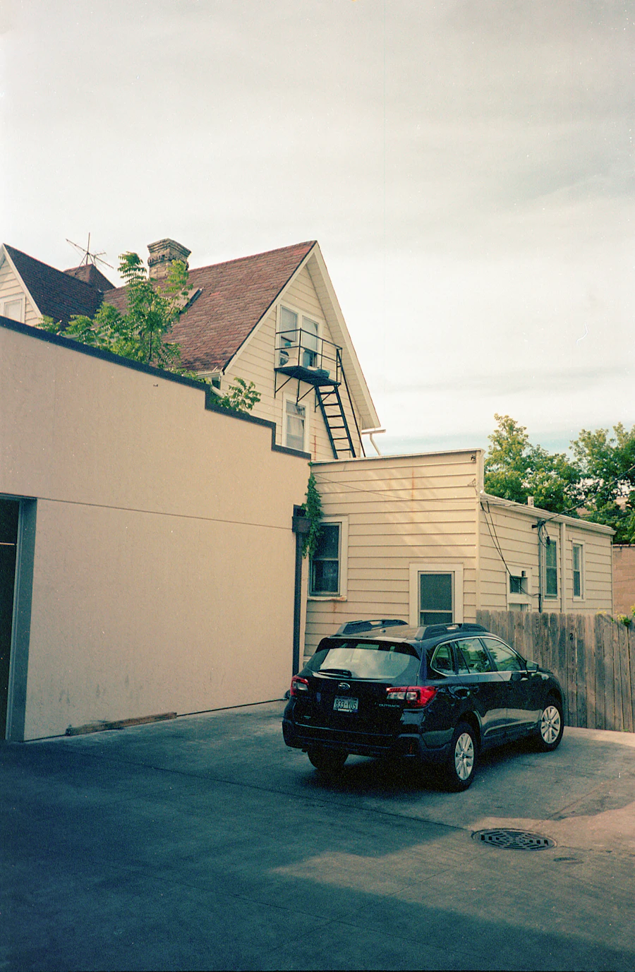 A car parked in a narrow driveway between older houses