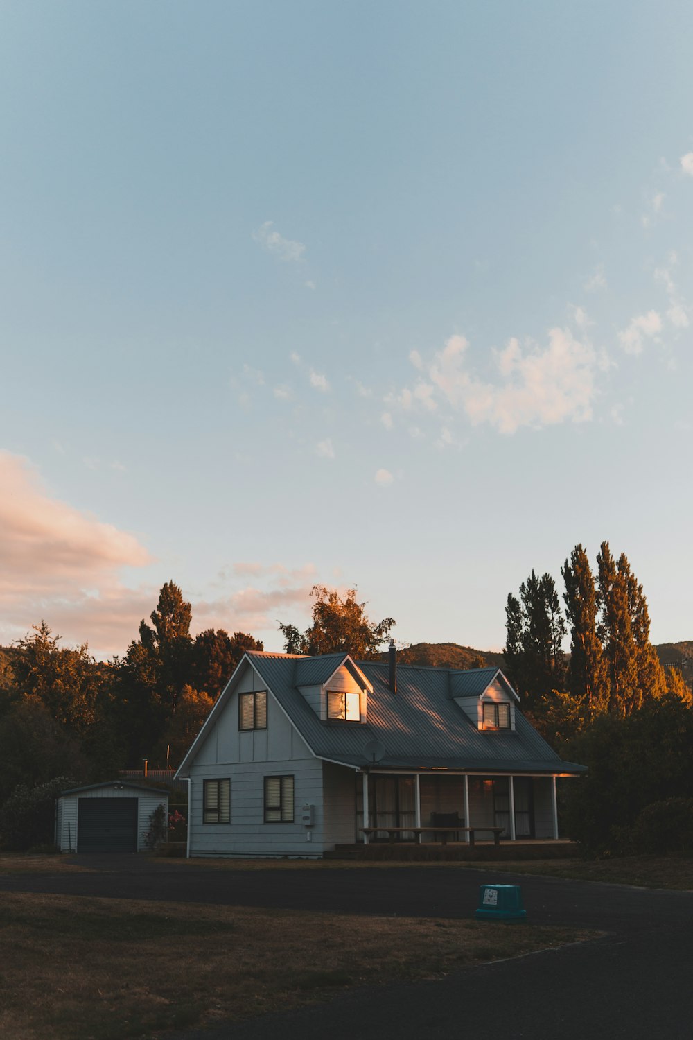 white and brown wooden house near trees under cloudy sky during daytime