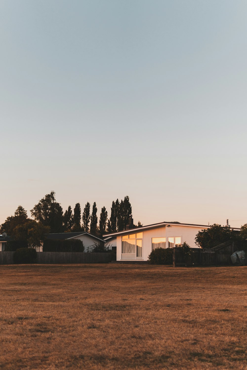 white and brown house near green trees under white sky during daytime