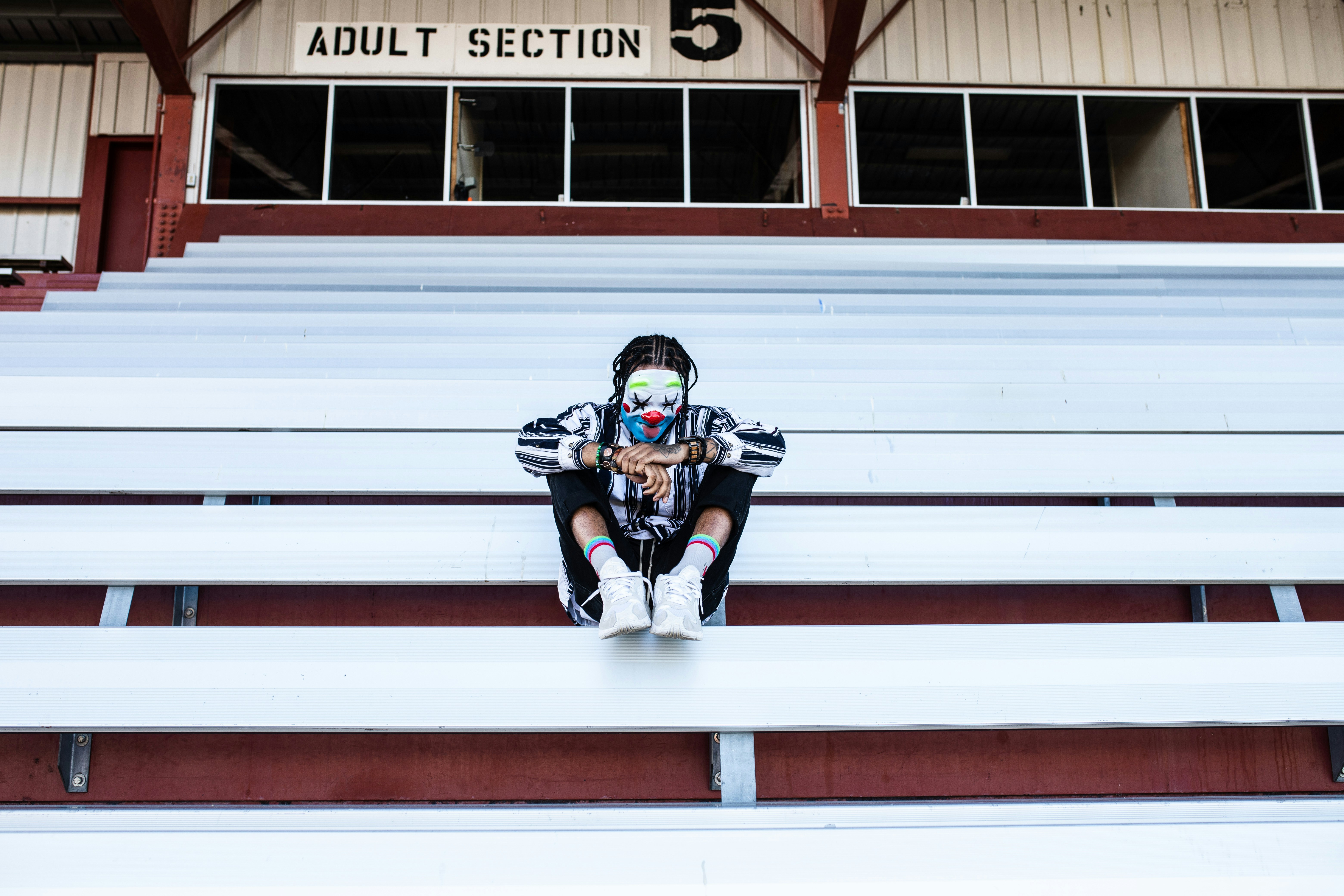 man in black jacket and blue denim jeans sitting on white and red concrete bench during