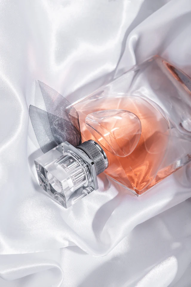 A clear glass perfume bottle on white cloth.