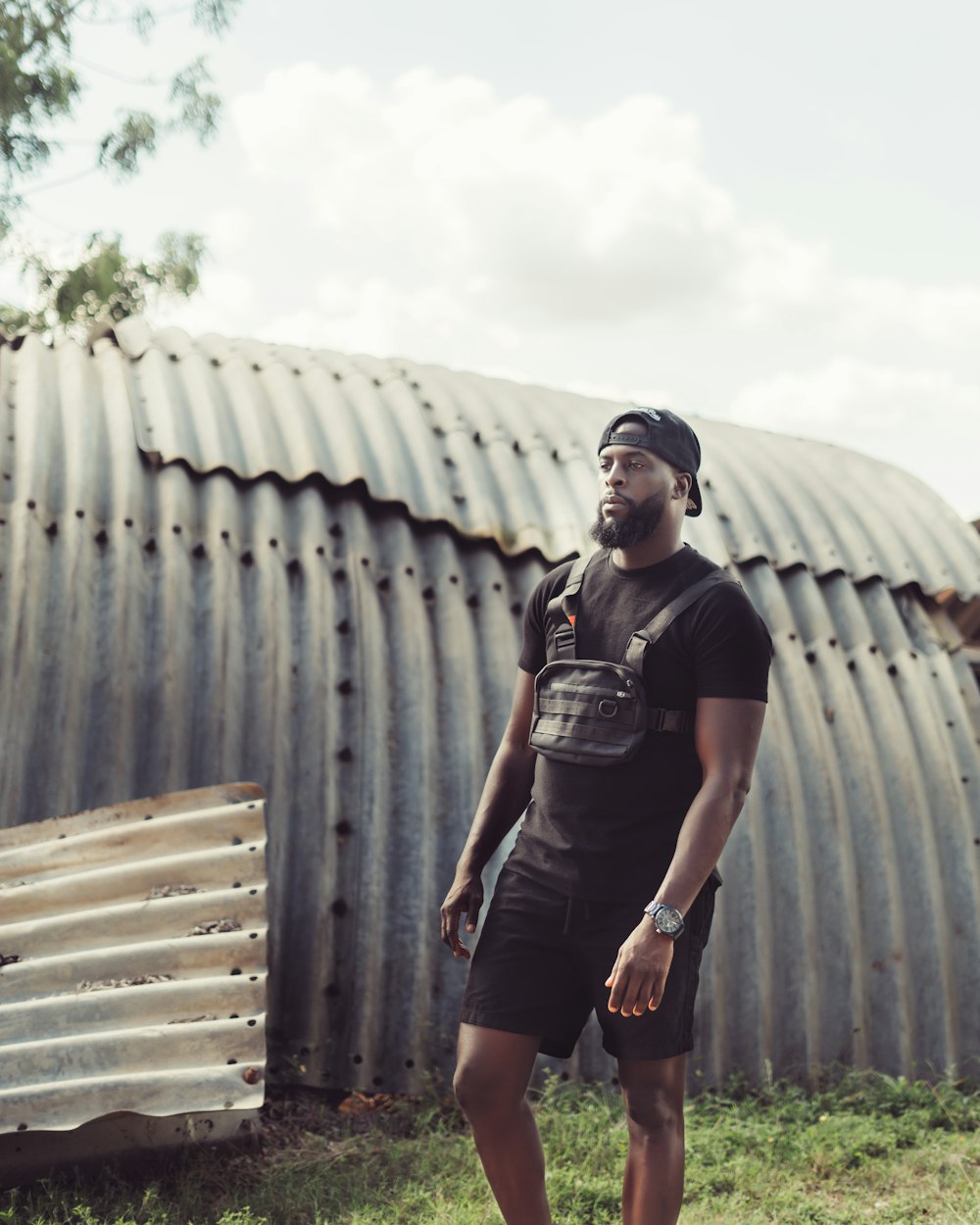 woman in black t-shirt and black shorts standing beside gray metal wall during daytime