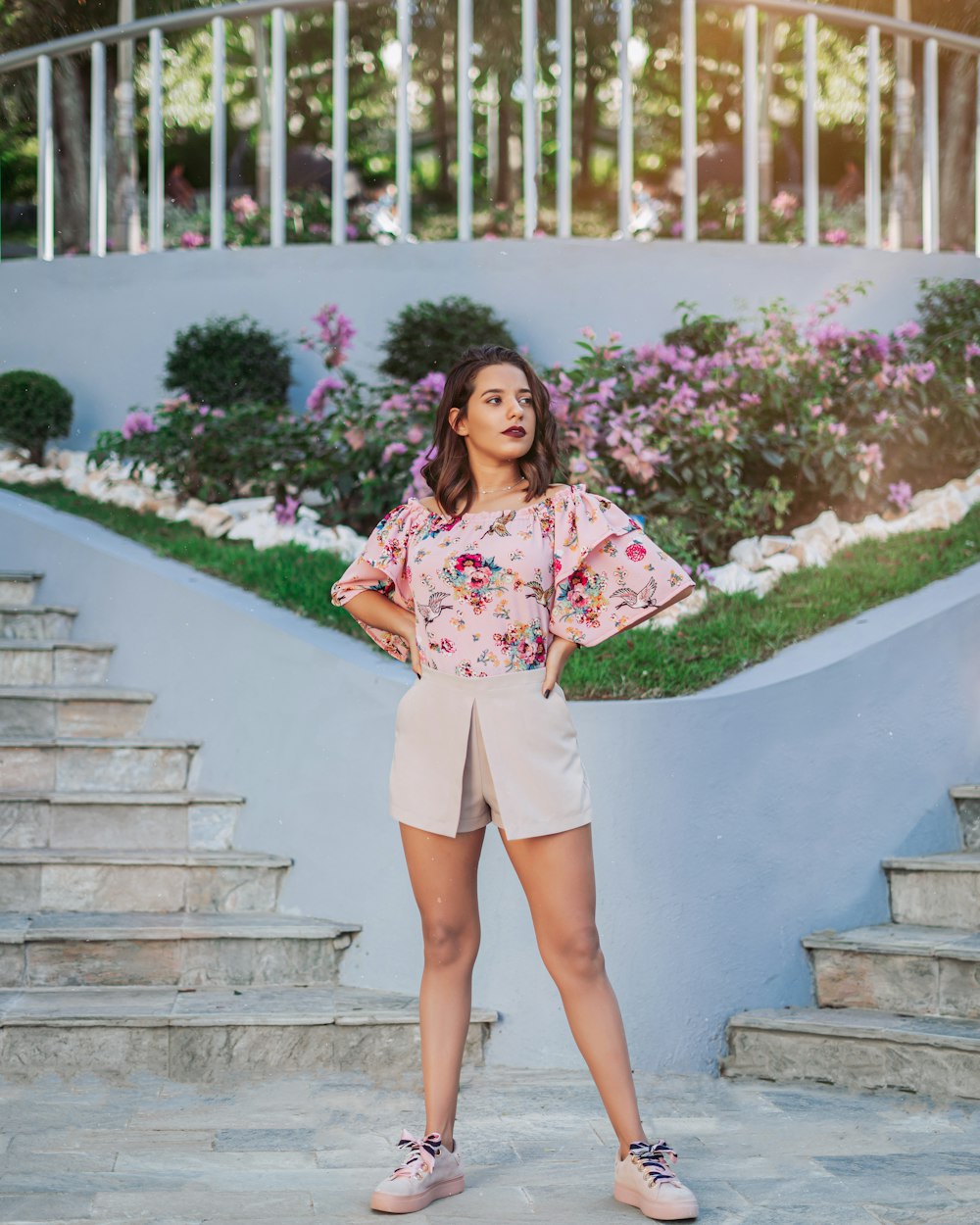 woman in pink and white floral dress standing on gray concrete stairs