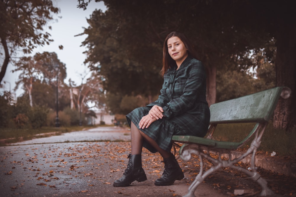 woman in black leather jacket sitting on brown wooden bench