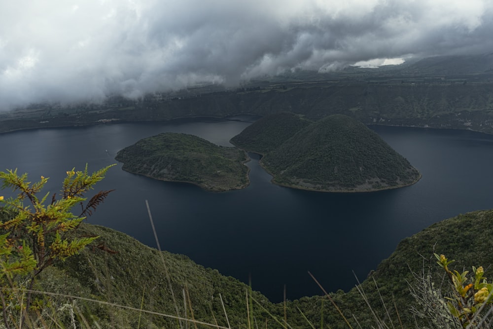 green mountain beside lake under white clouds during daytime