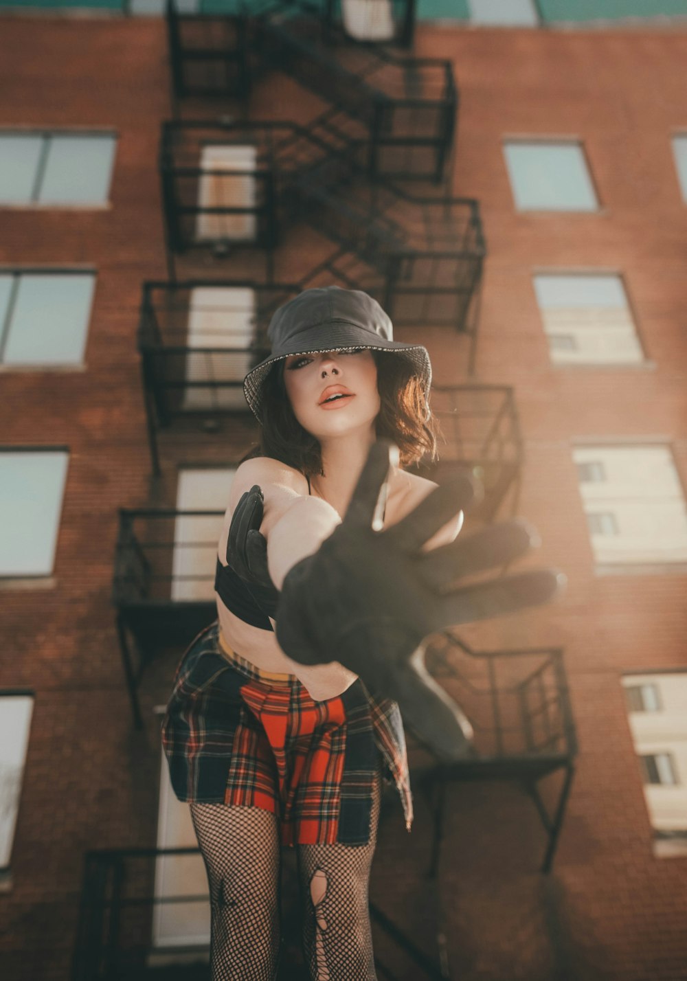 woman in black and red plaid long sleeve shirt standing near brown concrete building during daytime