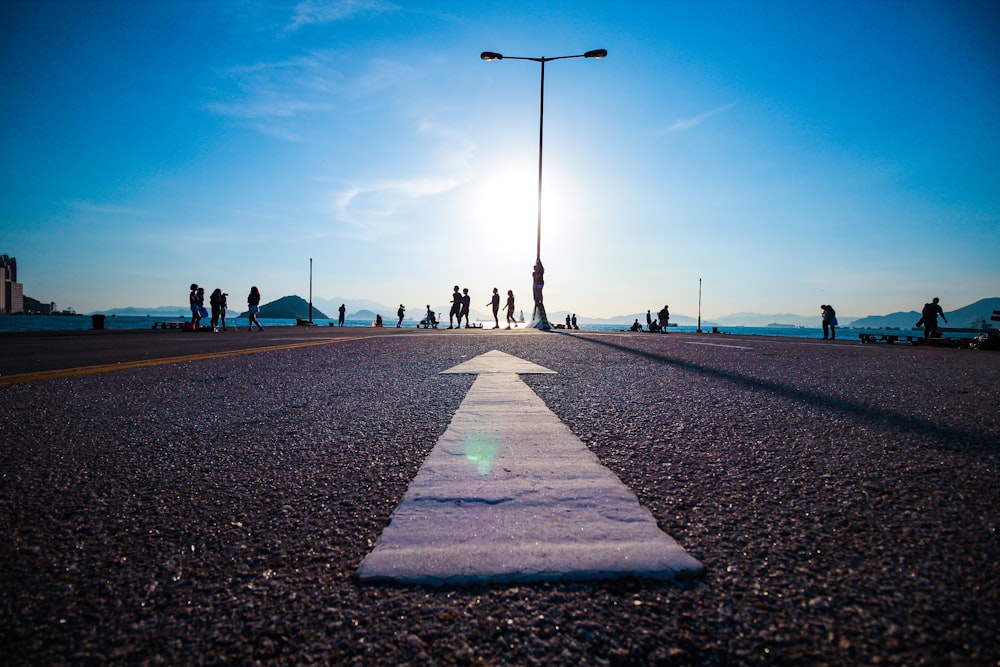 people walking on gray concrete pathway under blue sky during daytime