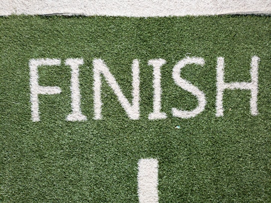 The word 'FINISH' is clearly written in large, white letters on a green, artificial turf surface, indicating the end of a race or event.