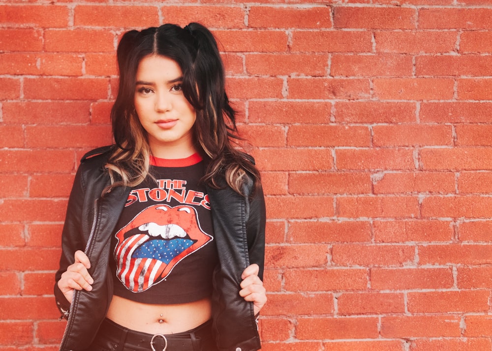 woman in black and red long sleeve shirt standing beside brown brick wall