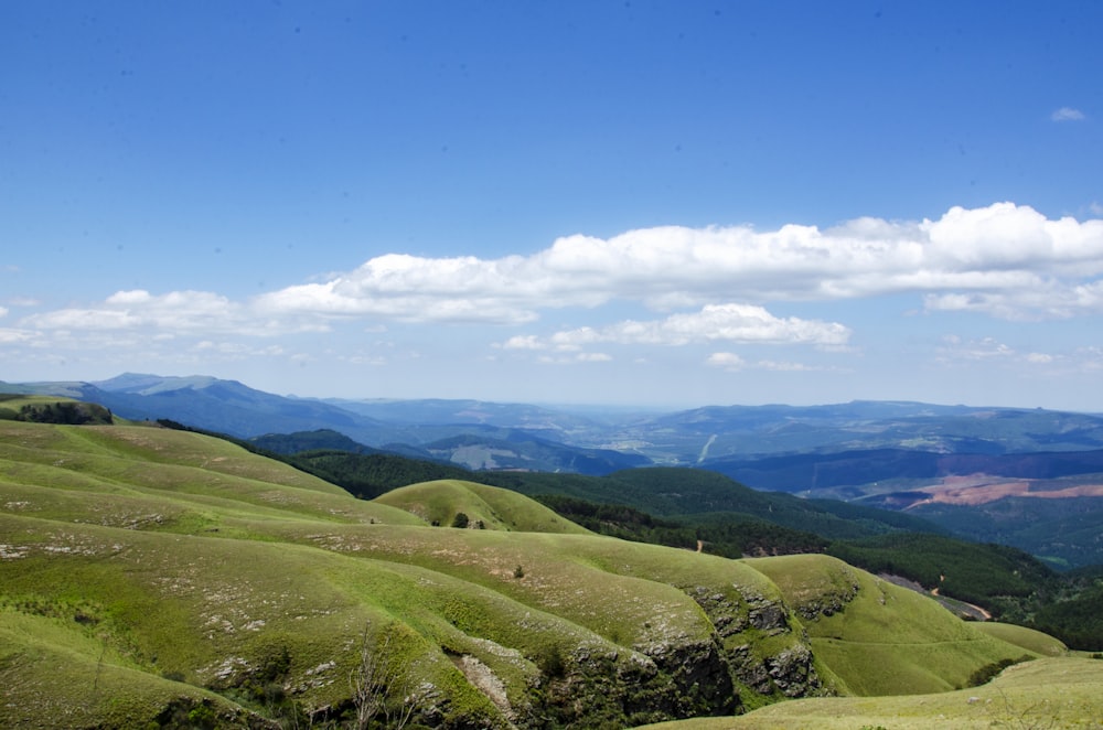 green grass field and mountains under blue sky during daytime