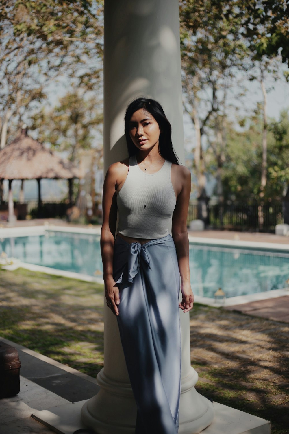 woman in white spaghetti strap dress standing near white concrete post during daytime