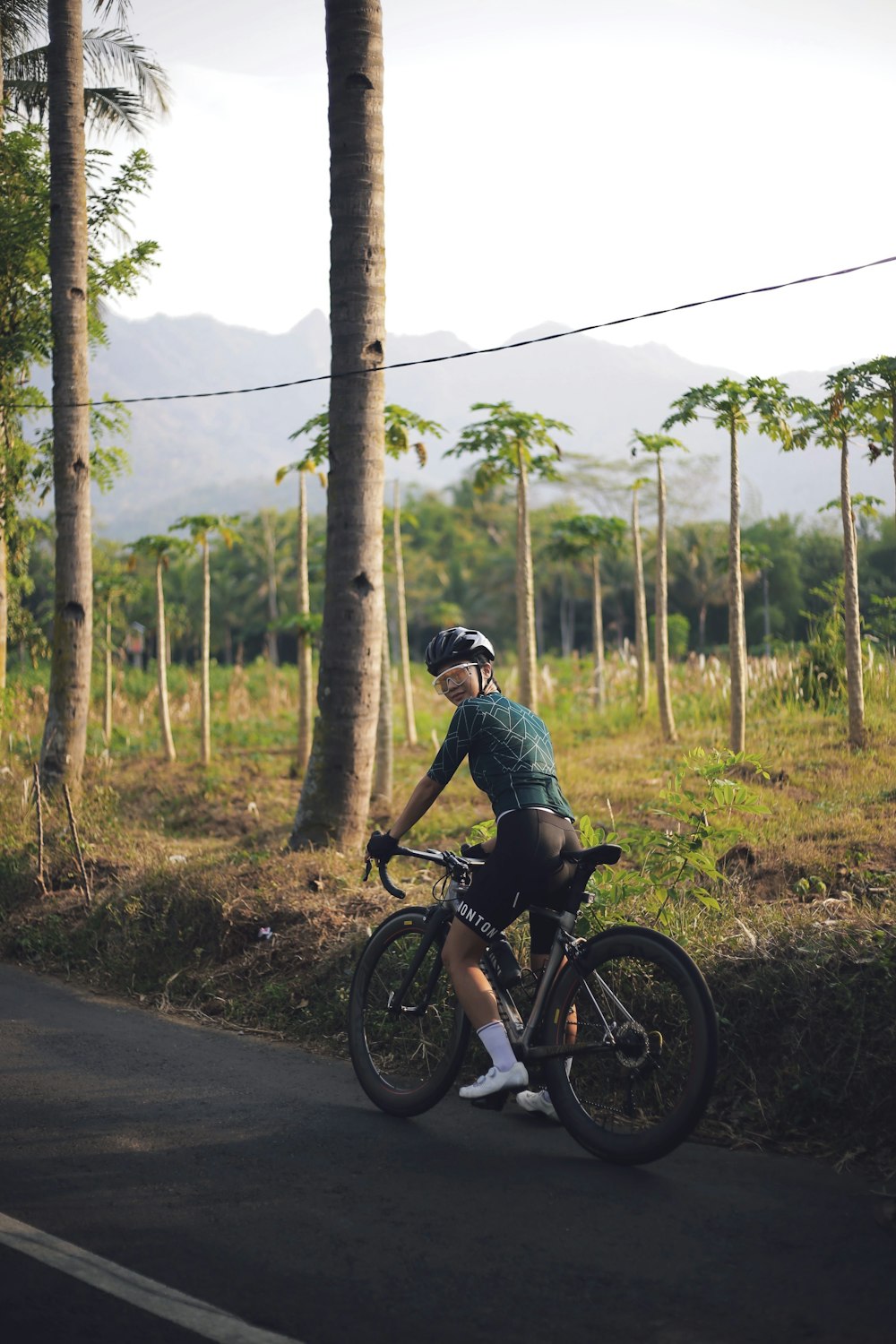 man in black and white shirt riding on black bicycle on road during daytime