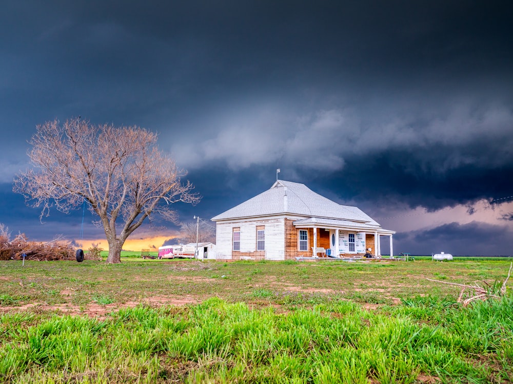 white and brown house near bare trees under gray cloudy sky during daytime