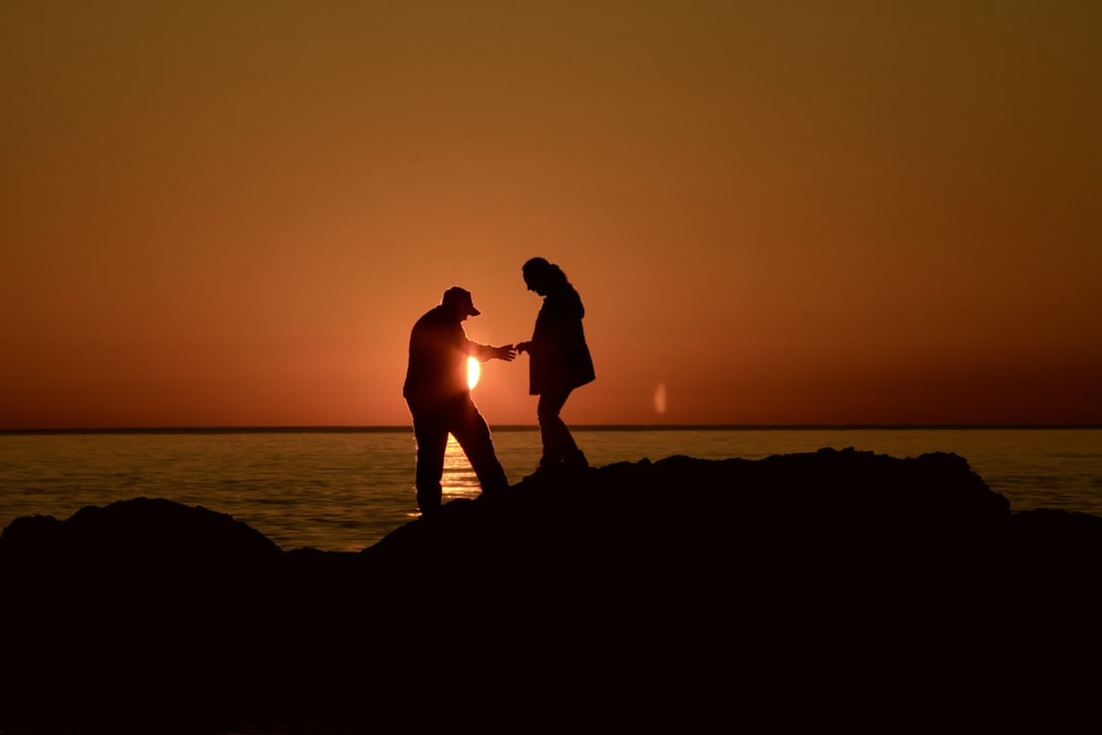 Silueta de hombre y mujer besándose durante la puesta del sol