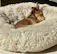 A cozy dog bed with a small brown dog peacefully sleeping inside.