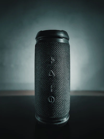 Sleek black Bluetooth speaker with glowing gold accents on a dark gradient background