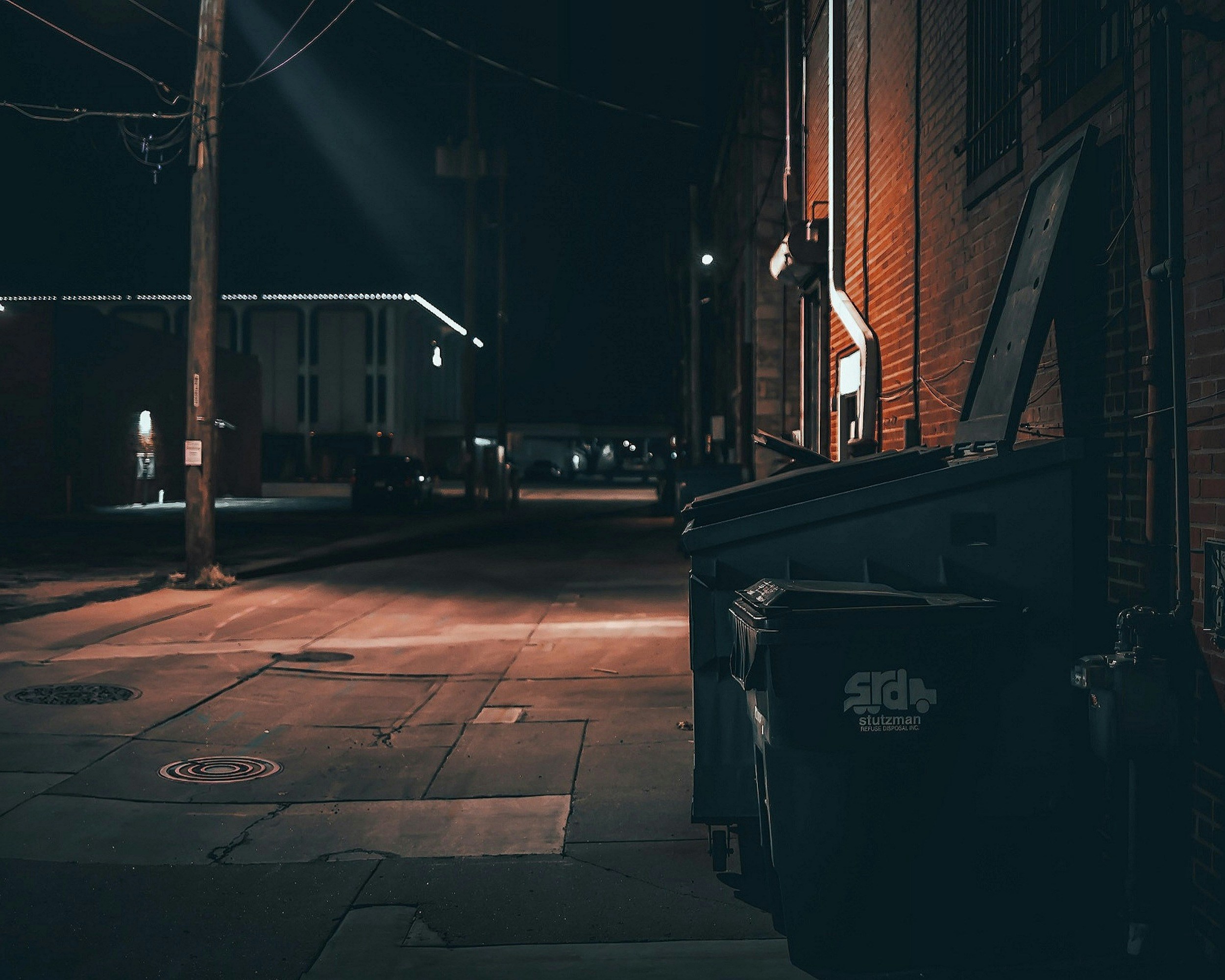 black trash bin on sidewalk during night time