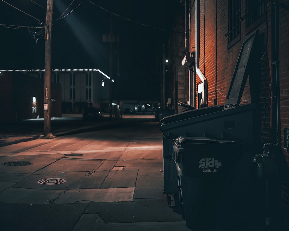 black trash bin on sidewalk during night time