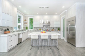 A bright, modern kitchen with sleek white cabinets and a large island bathed in natural light