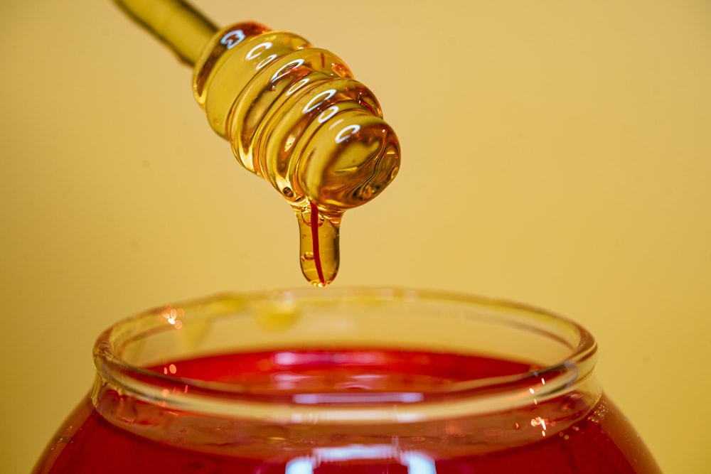 bouteille en verre transparent versant un liquide rouge sur du verre à boire transparent